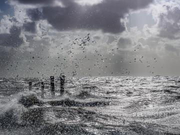 Die tobende Nordsee lässt ihre Wellen über den Tammwarft-Anleger schlagen. Eine Sturmflut ist auf Pellworm ein Erlebnis und bietet tolle Fotomotive.